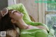 A woman in a green sweater laying on a wicker chair.