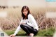 A woman sitting on the ground in a field of tall grass.