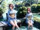 A couple of women sitting on top of a wooden dock.