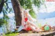 A woman sitting on the ground next to a tree.