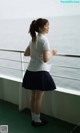 A woman in a white shirt and blue skirt standing on a balcony.