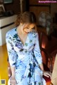 A woman in a blue floral dress sitting on a chair.