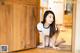 A woman crouching on the floor in front of a wooden door.