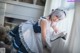 A woman in a maid outfit sitting on a window sill.