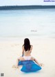 A woman in a bikini sitting on an inflatable raft on the beach.