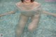 A woman in a white shirt is sitting in a pool.